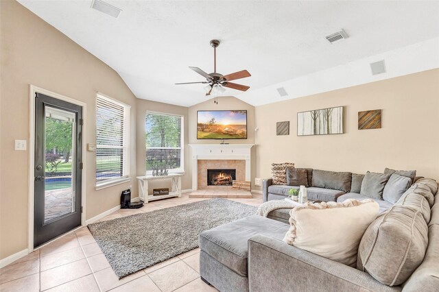 living room featuring vaulted ceiling, visible vents, light tile patterned flooring, a fireplace, and ceiling fan