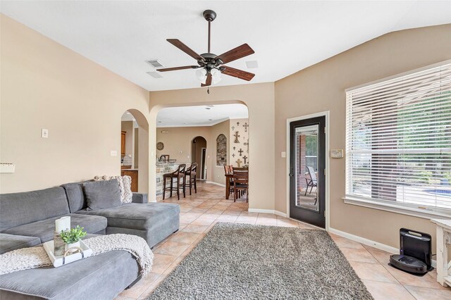 living room with baseboards, arched walkways, a ceiling fan, and light tile patterned flooring