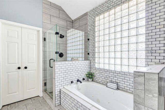 bathroom with tile patterned floors, a stall shower, tile walls, a whirlpool tub, and lofted ceiling