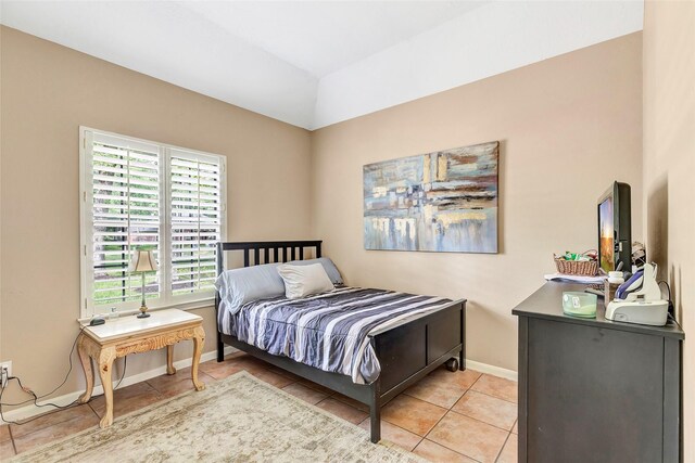 bedroom with baseboards, vaulted ceiling, and light tile patterned floors