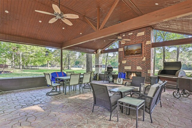 sunroom with outdoor dining area, an outdoor kitchen, an outdoor brick fireplace, and ceiling fan