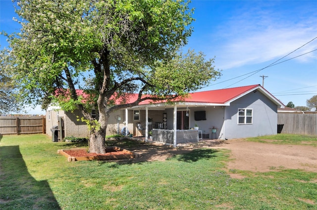 back of property featuring metal roof, a lawn, a fenced backyard, and stucco siding