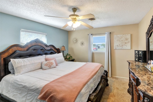 bedroom featuring a textured ceiling, visible vents, a ceiling fan, and light carpet