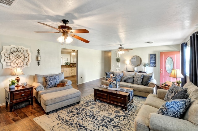 living room with wood finished floors, visible vents, and a ceiling fan