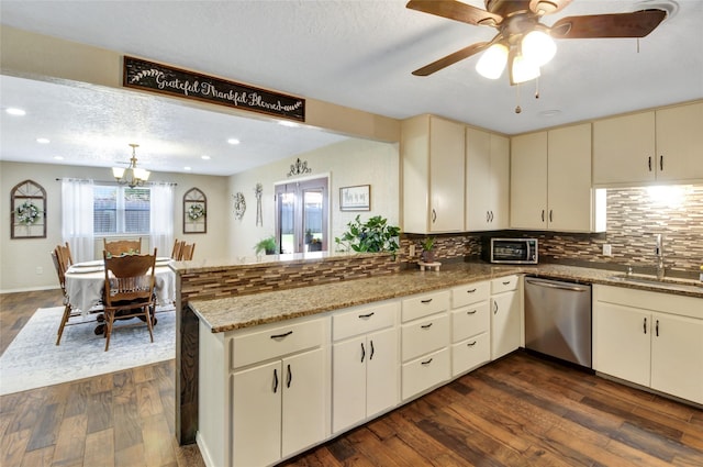 kitchen with backsplash, stainless steel dishwasher, a sink, dark wood-type flooring, and a peninsula