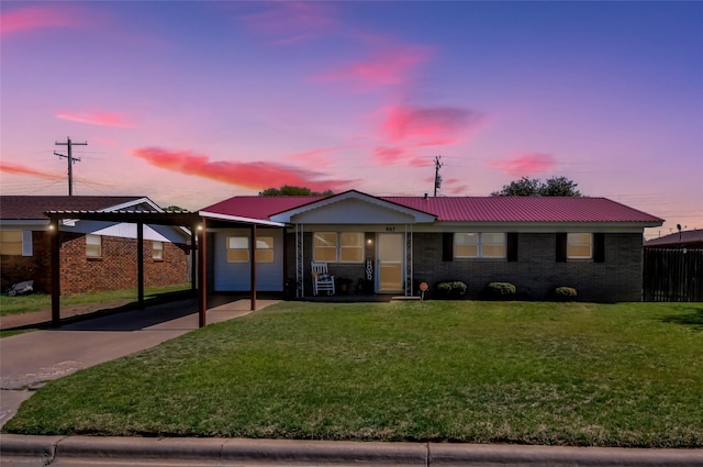 view of front of property with a front lawn, driveway, a carport, and metal roof