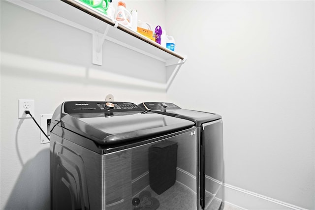 clothes washing area featuring laundry area, baseboards, and washing machine and dryer