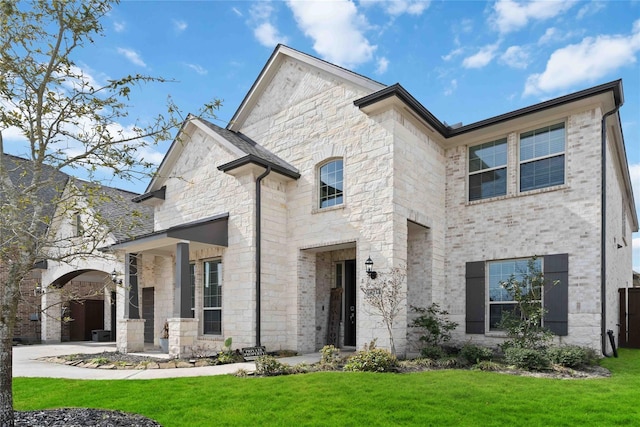 french country inspired facade featuring stone siding and a front yard