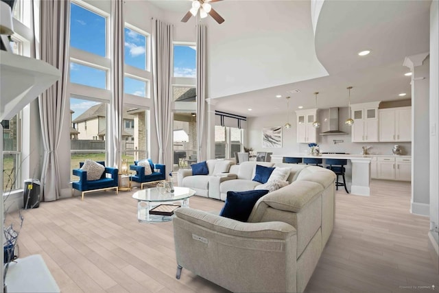 living room featuring recessed lighting, light wood-style flooring, ceiling fan, and a high ceiling