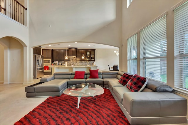 living room featuring arched walkways, a high ceiling, and plenty of natural light