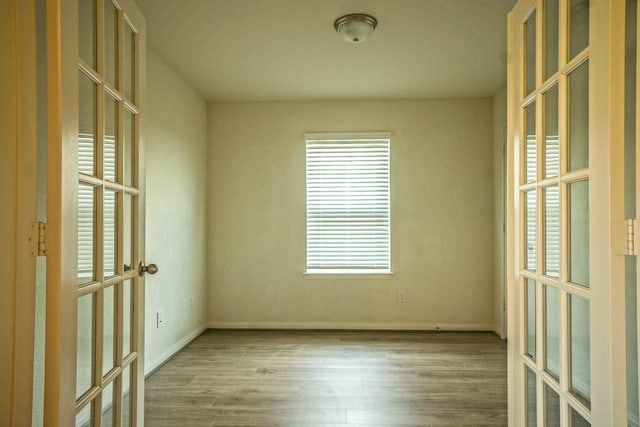 unfurnished room featuring french doors, wood finished floors, and baseboards