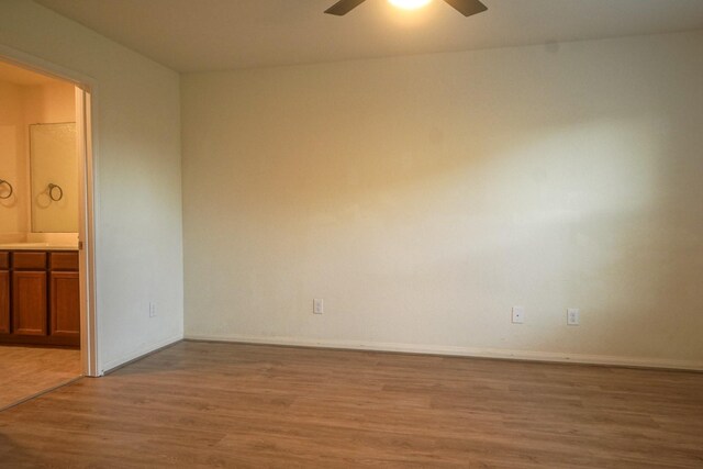 empty room featuring wood finished floors, ceiling fan, and baseboards