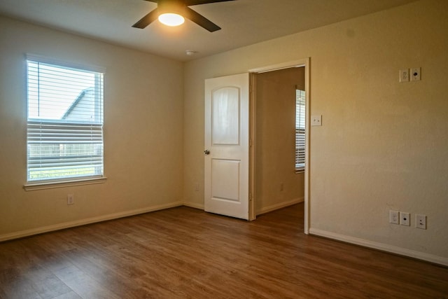 spare room featuring wood finished floors, ceiling fan, plenty of natural light, and baseboards