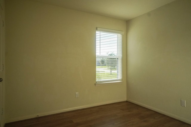 unfurnished room with dark wood-style flooring and baseboards