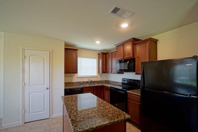kitchen with black appliances, a sink, dark stone counters, a center island, and light tile patterned flooring