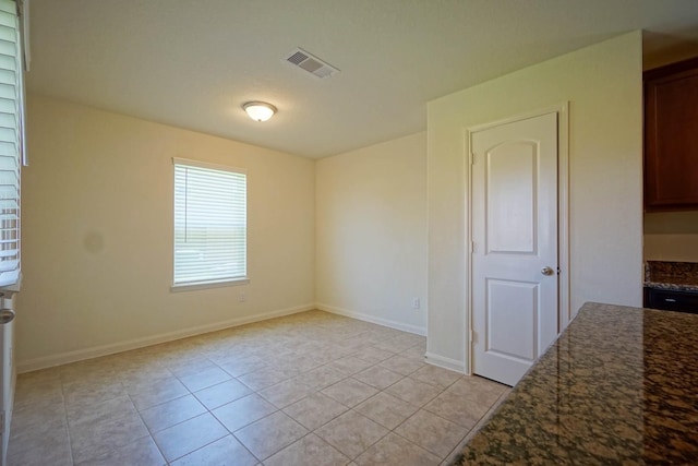 empty room featuring light tile patterned flooring and baseboards