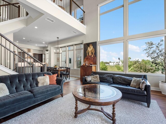 living area with a towering ceiling, wood finished floors, and visible vents