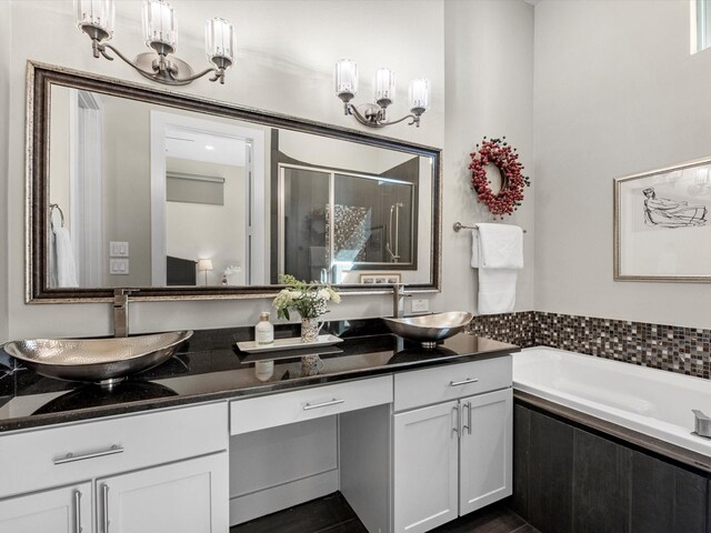 full bath featuring a stall shower, a garden tub, double vanity, and a sink