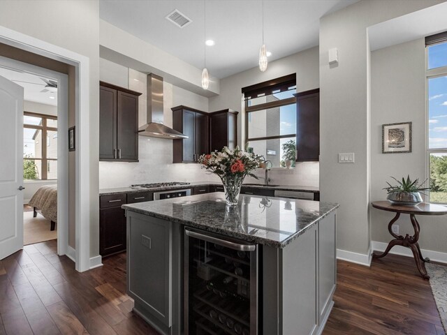 kitchen with dark stone counters, visible vents, dark wood-style floors, wall chimney exhaust hood, and wine cooler