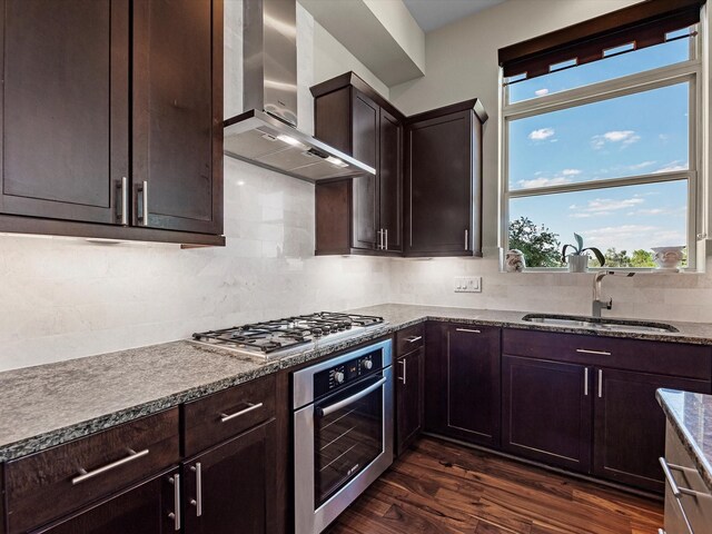 kitchen featuring stainless steel appliances, a wealth of natural light, wall chimney range hood, and a sink