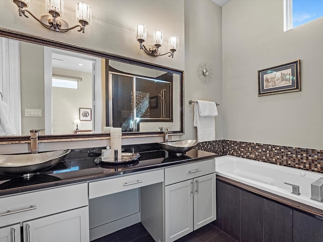 full bath featuring an inviting chandelier, double vanity, a bath, and a sink