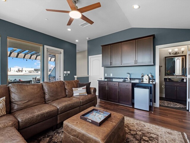 living room with dark wood finished floors, vaulted ceiling, visible vents, a ceiling fan, and indoor wet bar
