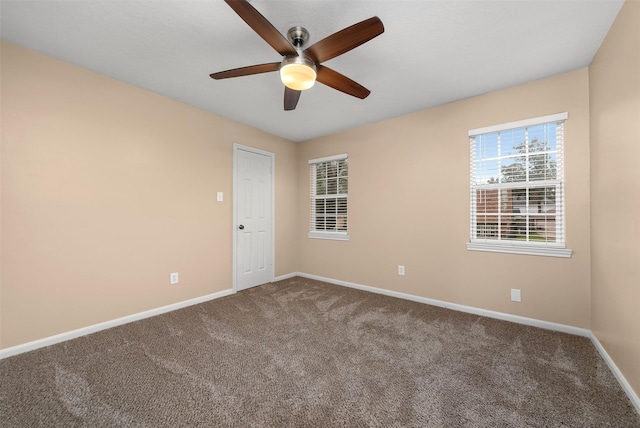 carpeted spare room featuring ceiling fan and baseboards