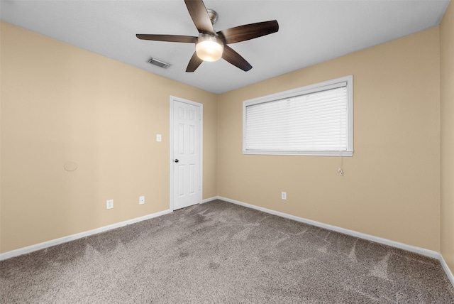 carpeted spare room featuring baseboards, visible vents, and ceiling fan