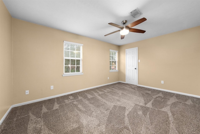 carpeted empty room with visible vents, baseboards, and ceiling fan