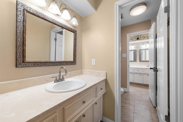 bathroom with toilet, vanity, tile patterned floors, and baseboards