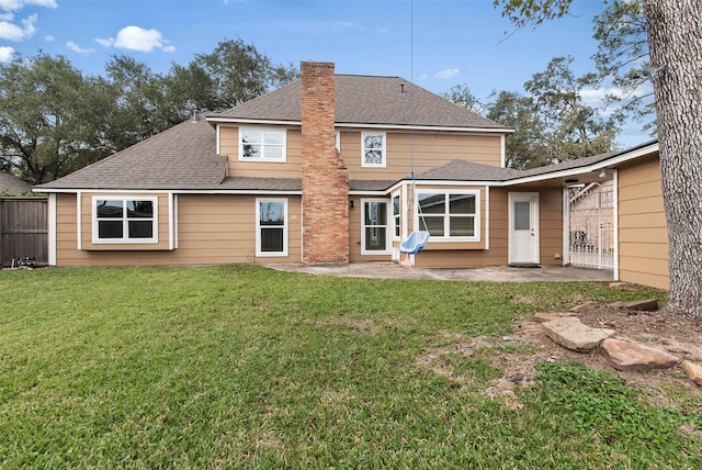 back of house featuring a chimney, a shingled roof, fence, a yard, and a patio