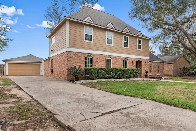 traditional-style house featuring a front lawn, brick siding, a garage, a shingled roof, and an outdoor structure
