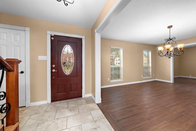 foyer with wood finished floors, baseboards, and an inviting chandelier