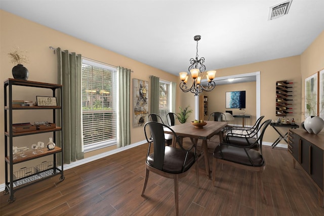 dining area featuring baseboards, visible vents, a chandelier, and dark wood-style floors