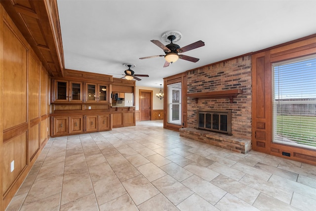 unfurnished living room featuring a ceiling fan, a brick fireplace, and wooden walls