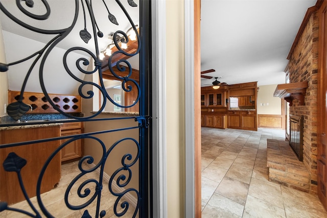 interior details featuring a fireplace, a ceiling fan, and a wainscoted wall
