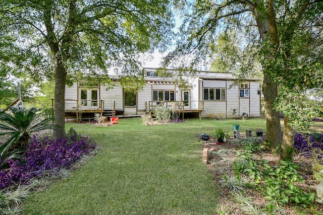 rear view of property featuring a yard, a deck, and french doors
