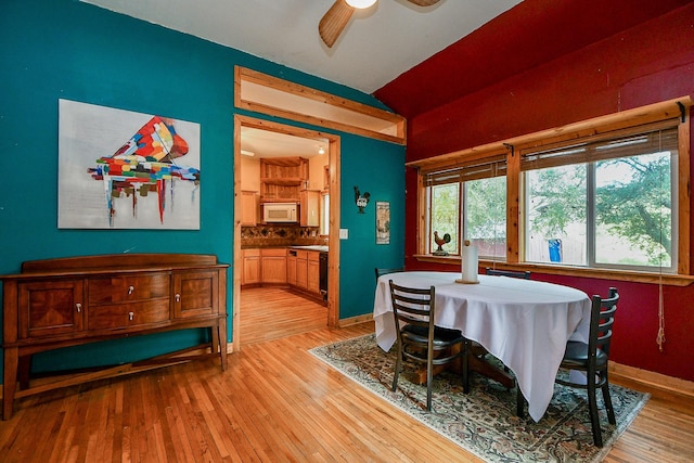 dining room featuring ceiling fan, vaulted ceiling, light wood-style floors, and baseboards