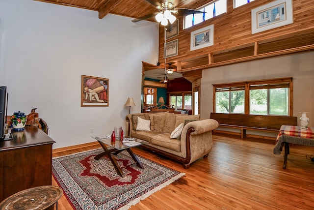 living room featuring a high ceiling, a ceiling fan, and light wood-style floors