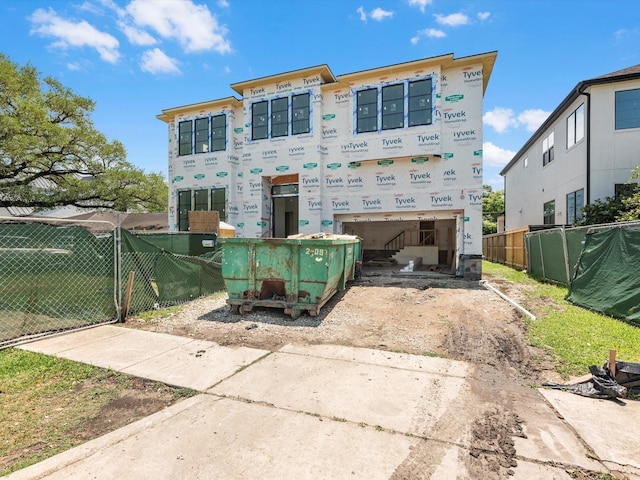 back of house with fence, driveway, and a garage