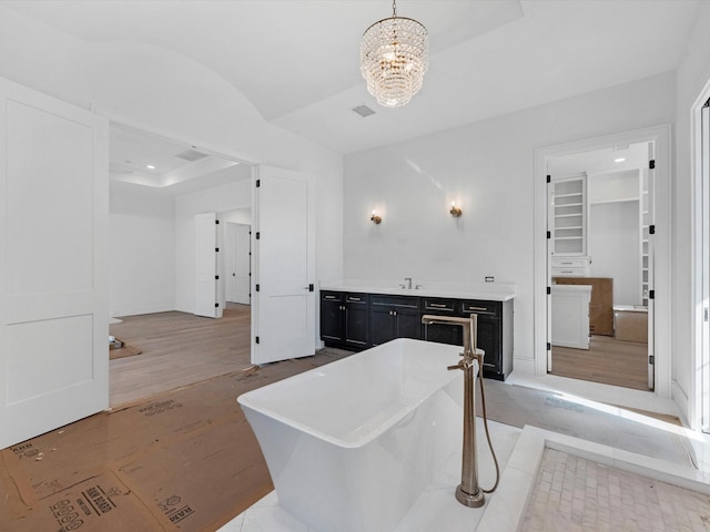 bathroom with a sink, vaulted ceiling, visible vents, an inviting chandelier, and a freestanding tub