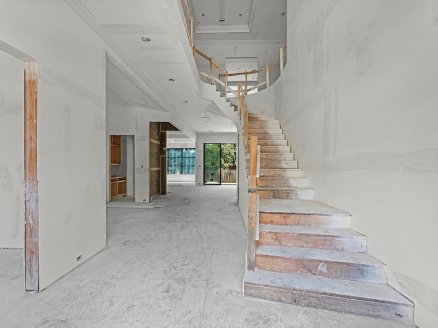 stairs featuring a towering ceiling and crown molding