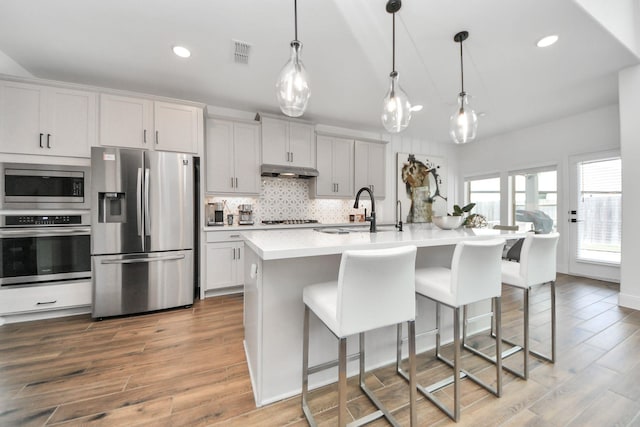 30706 Thicket Ct, Fulshear, TX 77441 - kitchen with a sink, visible vents, wood finished floors, under cabinet range hood, and appliances with stainless steel finishes