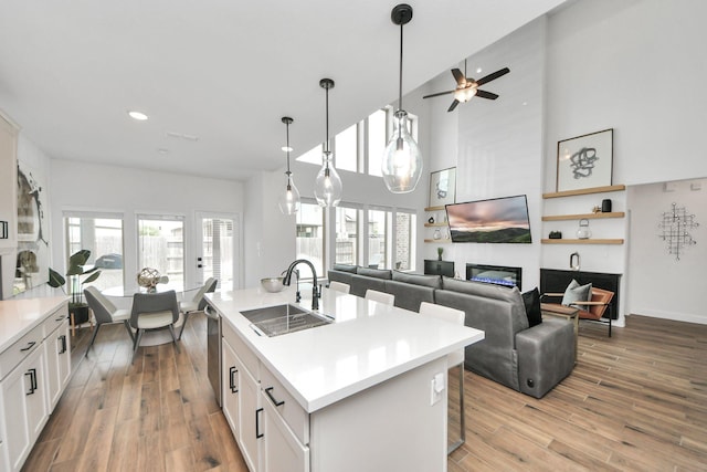 30706 Thicket Ct, Fulshear, TX 77441 - kitchen with a sink, light wood-style floors, light countertops, a fireplace, and white cabinetry
