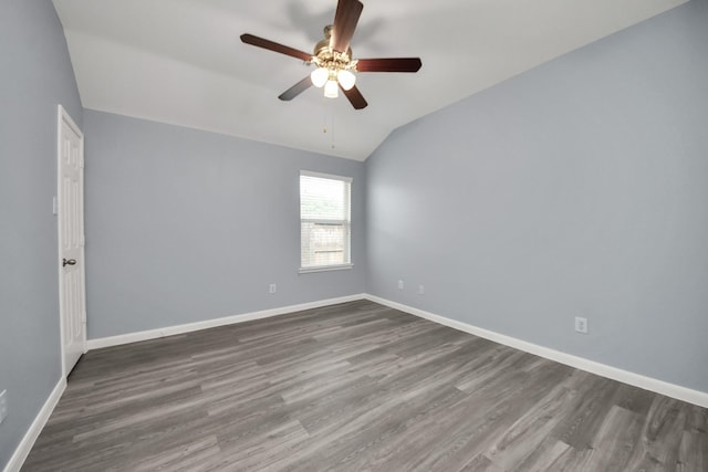 spare room featuring dark wood finished floors, vaulted ceiling, and ceiling fan