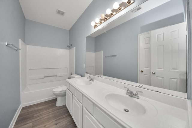 full bathroom with wood finished floors, a sink, double vanity, and toilet