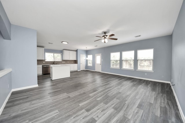 unfurnished living room featuring ceiling fan, baseboards, dark wood-style flooring, and a sink