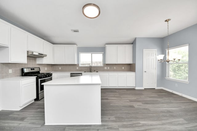 kitchen featuring a notable chandelier, tasteful backsplash, a sink, appliances with stainless steel finishes, and under cabinet range hood