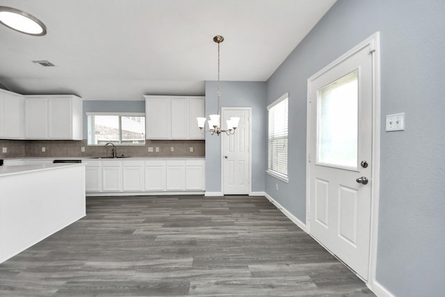 kitchen featuring white cabinets, a sink, plenty of natural light, a notable chandelier, and decorative backsplash