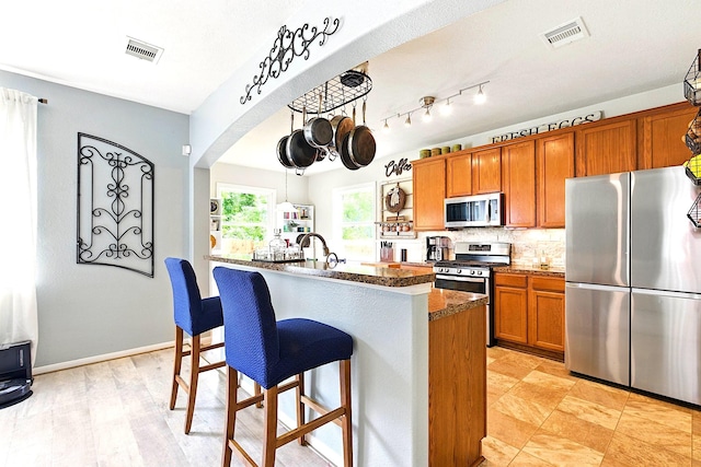 16611 River Wood Ct, Crosby, TX 77532 - kitchen with visible vents, stainless steel appliances, a kitchen bar, and brown cabinets